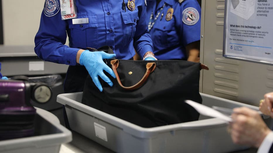 FILE- A Transportation Security Administration (TSA) worker screens luggage at LaGuardia Airport (LGA)